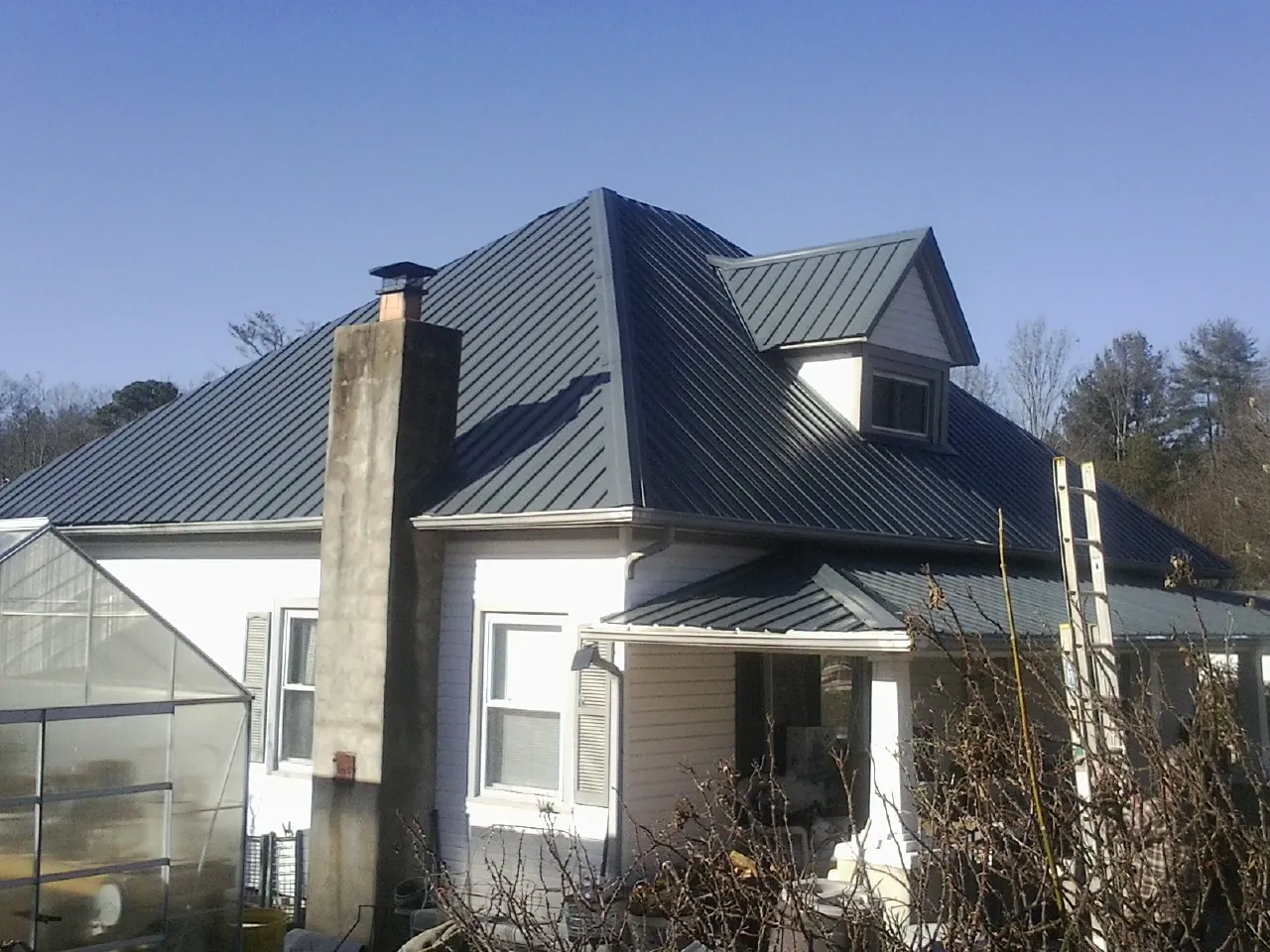 Dark blue standing seam metal roof on a white farmhouse with dormer — Slate & Tile Roof Repair by Roofing Brothers in Pasadena