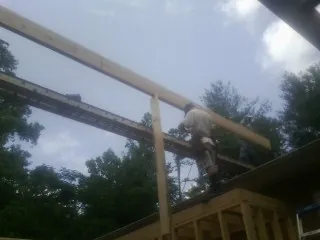 Carpenter setting a ridge beam over a new addition frame — Ice Dam Removal by Roofing Brothers in Pasadena