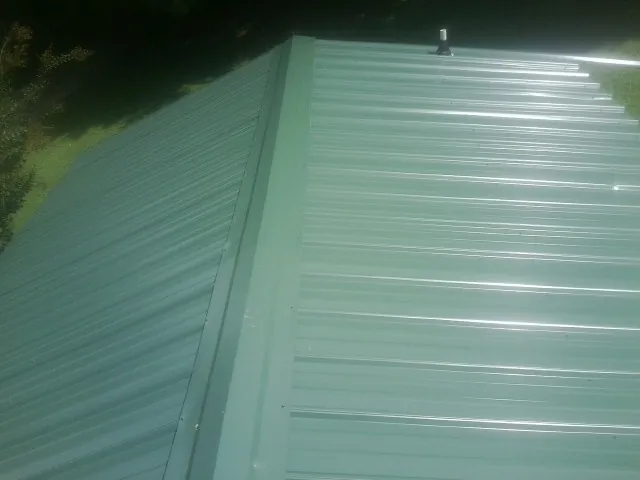 New green metal panels meeting at the ridge of a roof — Flat Roof Repair work by our crew in Pasadena