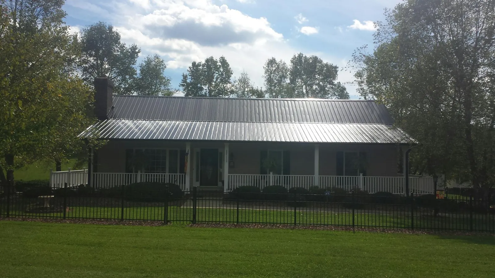 Gray metal roof on a brick ranch with a full width front porch — Gutter Guard Installation work by our crew in Pasadena