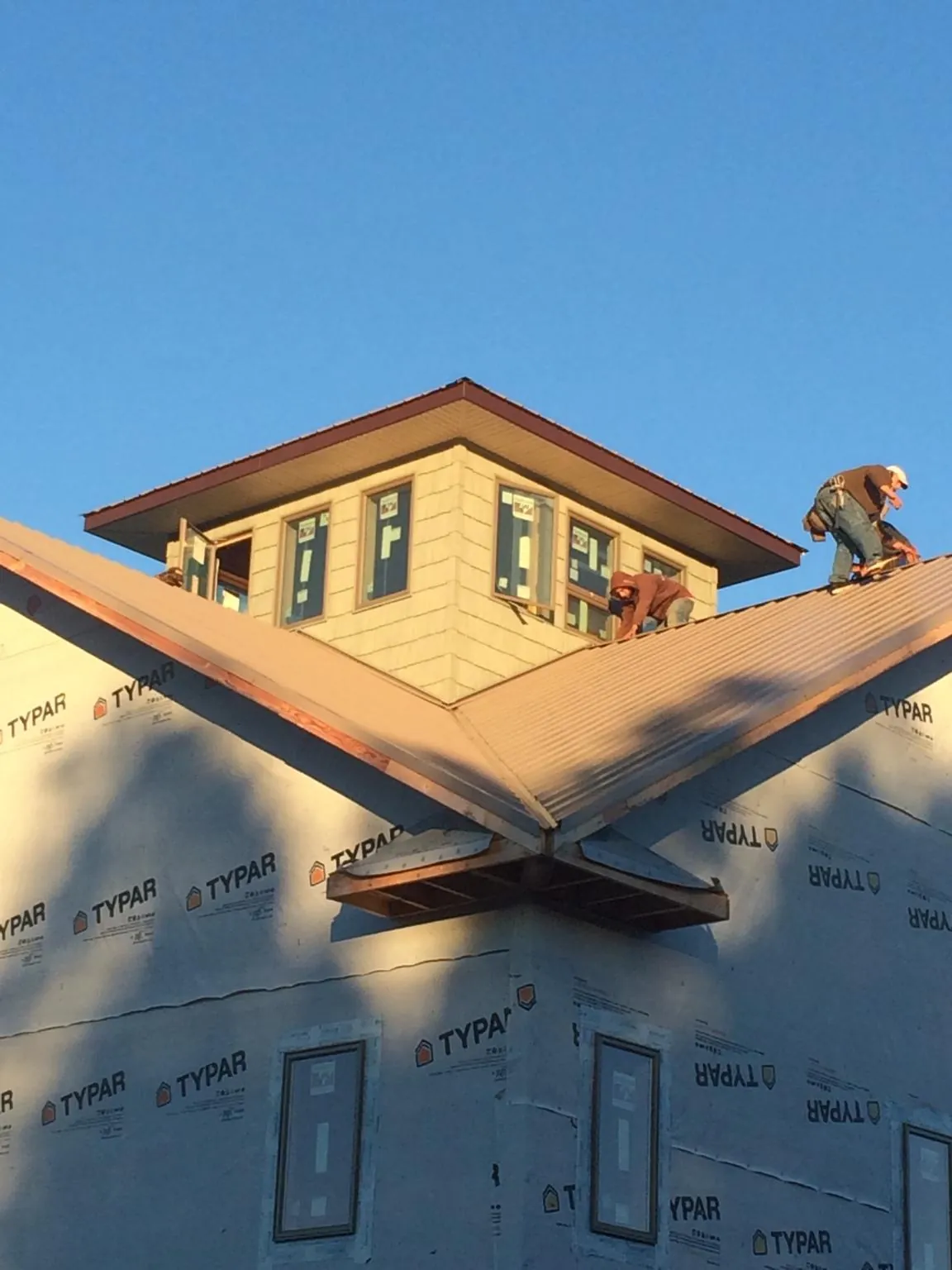 Roofers working around a rooftop cupola on a new metal roof at sunset — Roof Waterproofing in Pasadena by Roofing Brothers